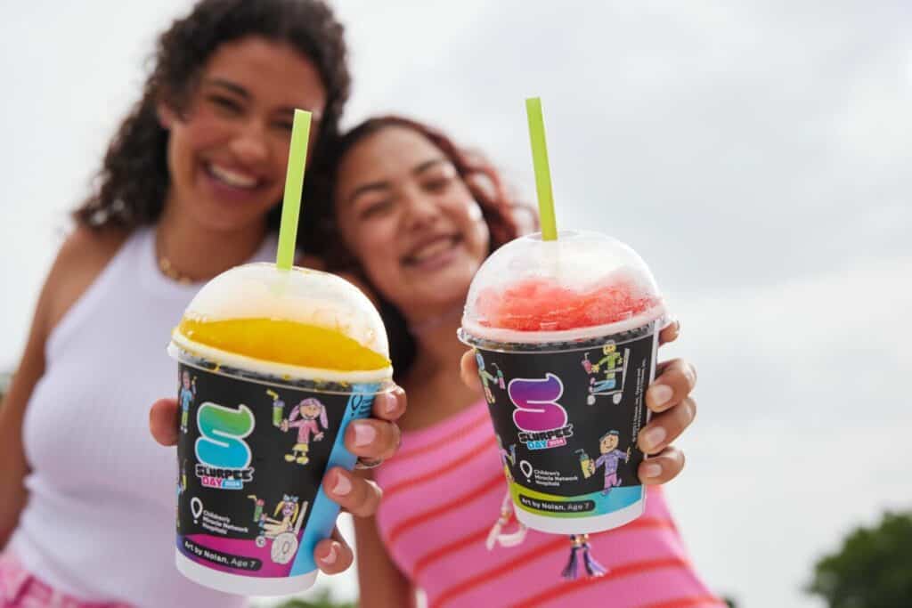 Two people holding Slurpees