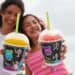 Two people holding Slurpees