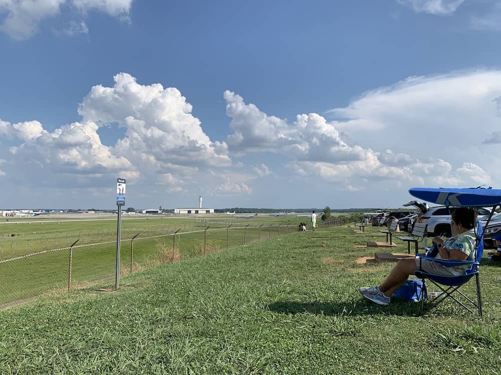 People in folding chairs watching planes take off.