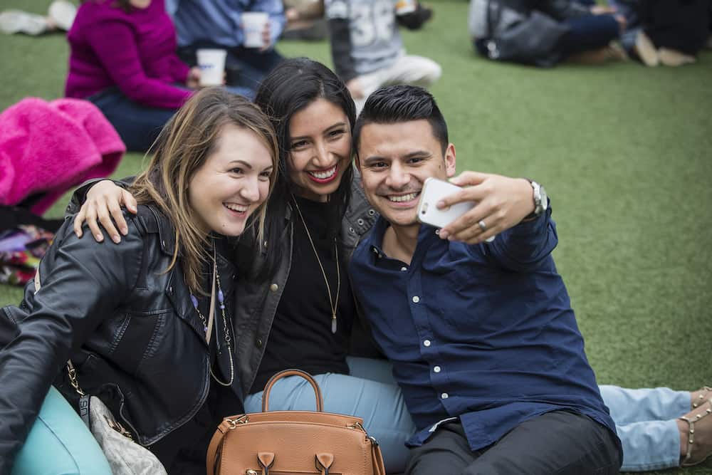 three friends watching a concert, taking a selfie