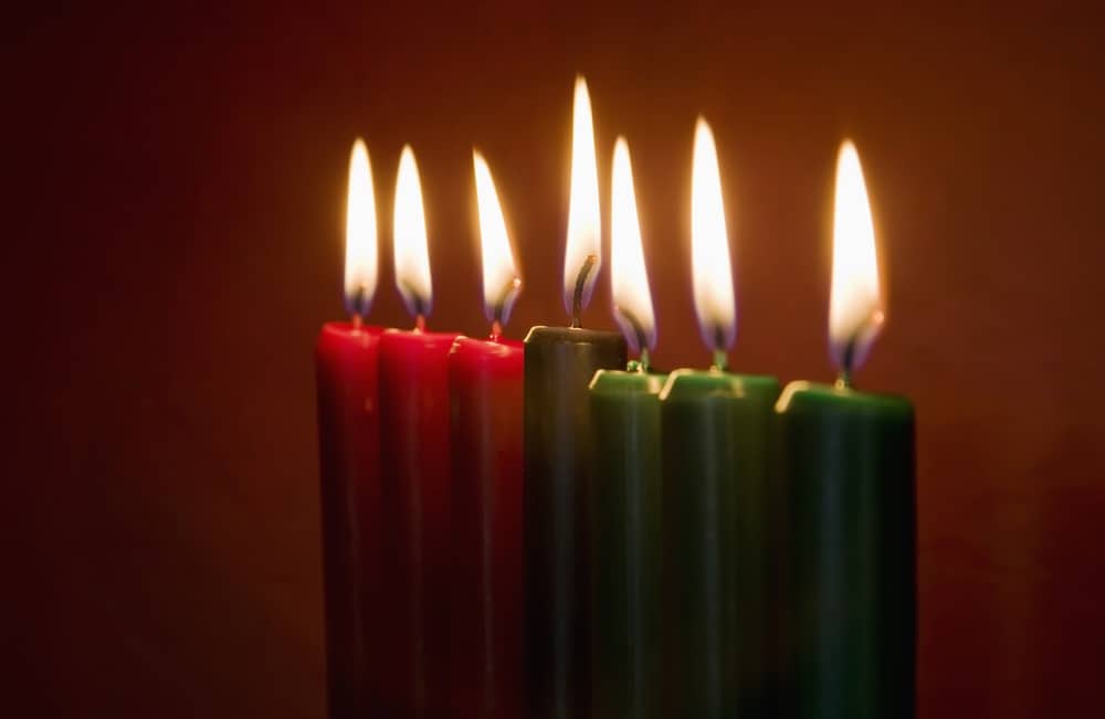 Seven Kwanzaa candles with flames lit on neutral background