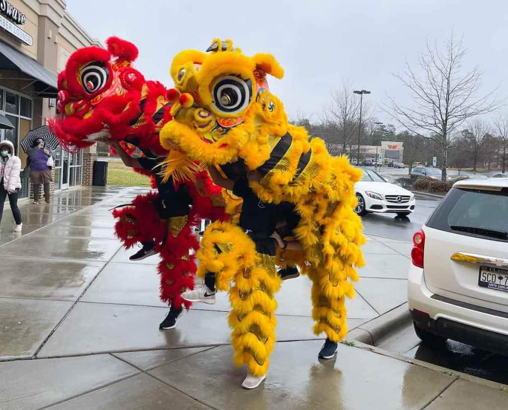 Red and yellow costumed performers doing lion dance for Chinese New Year
