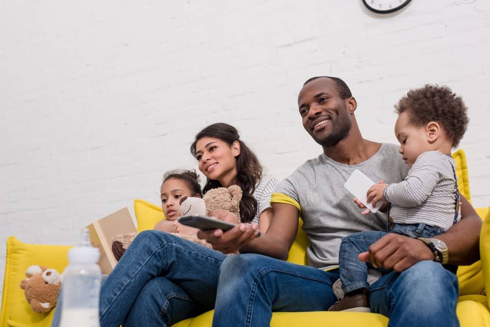 Family on a yellow couch watching TV