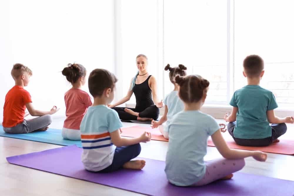 Children practicing yoga with their teacher in the gym