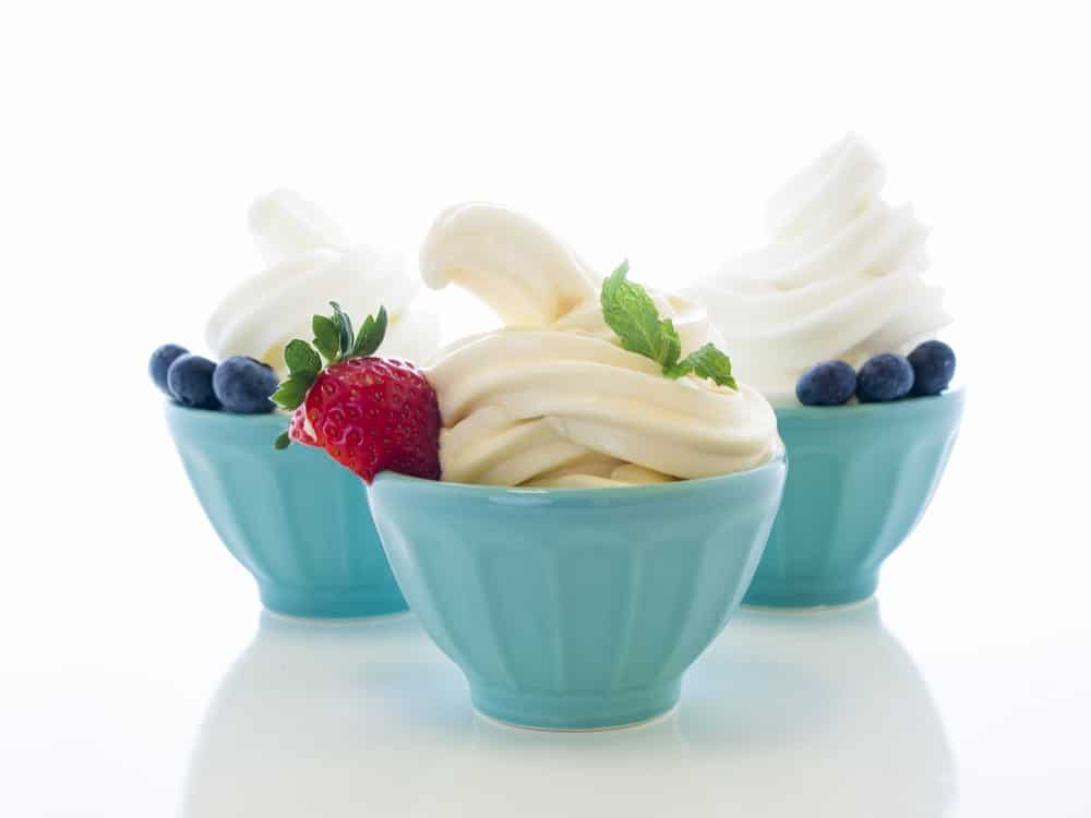 Cups of soft-serve frozen yogurt on white background.
