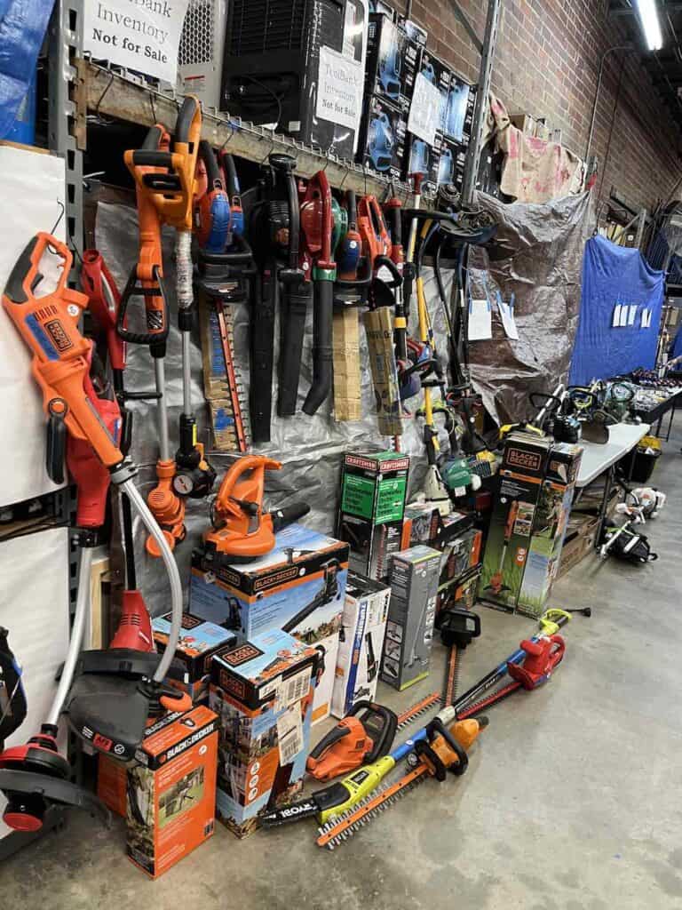 Weed whackers, leaf blowers and other powered lawn tools hanging on rack and on floor for sale