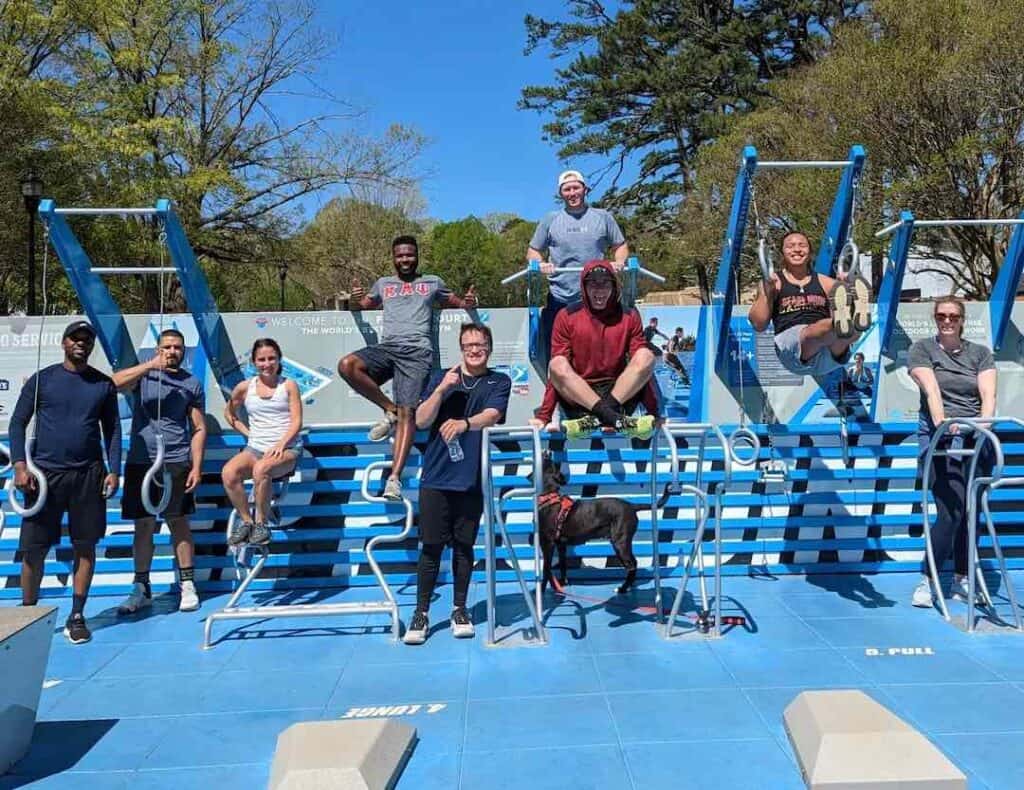 9 people and a dog on fitness equipment in a park