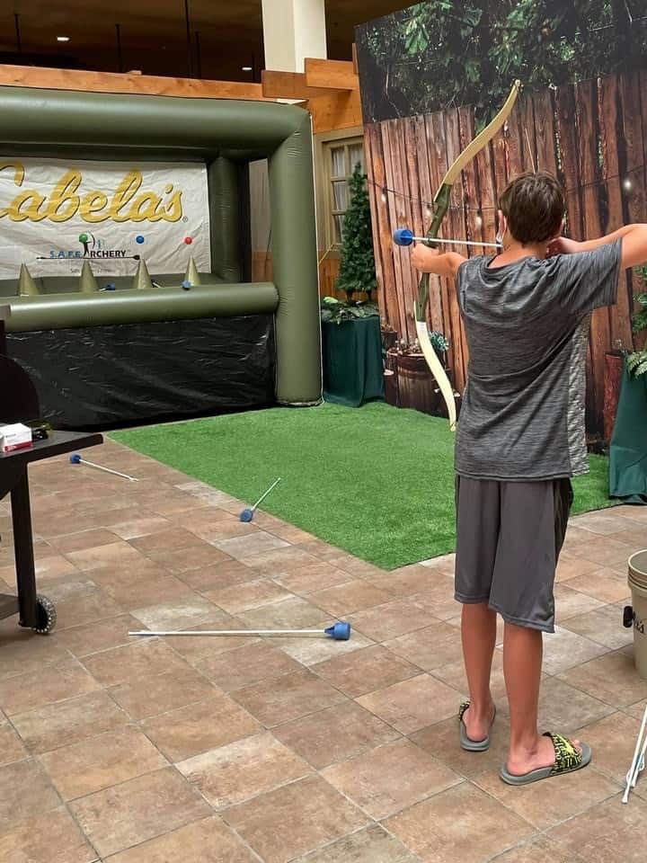 boy shooting an arrow at an inflatable game at Cabela's