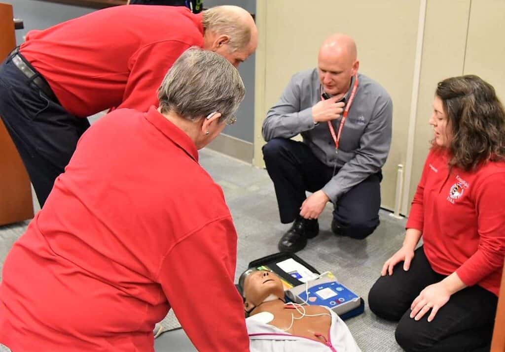 Four people practicing CPR on a dummy