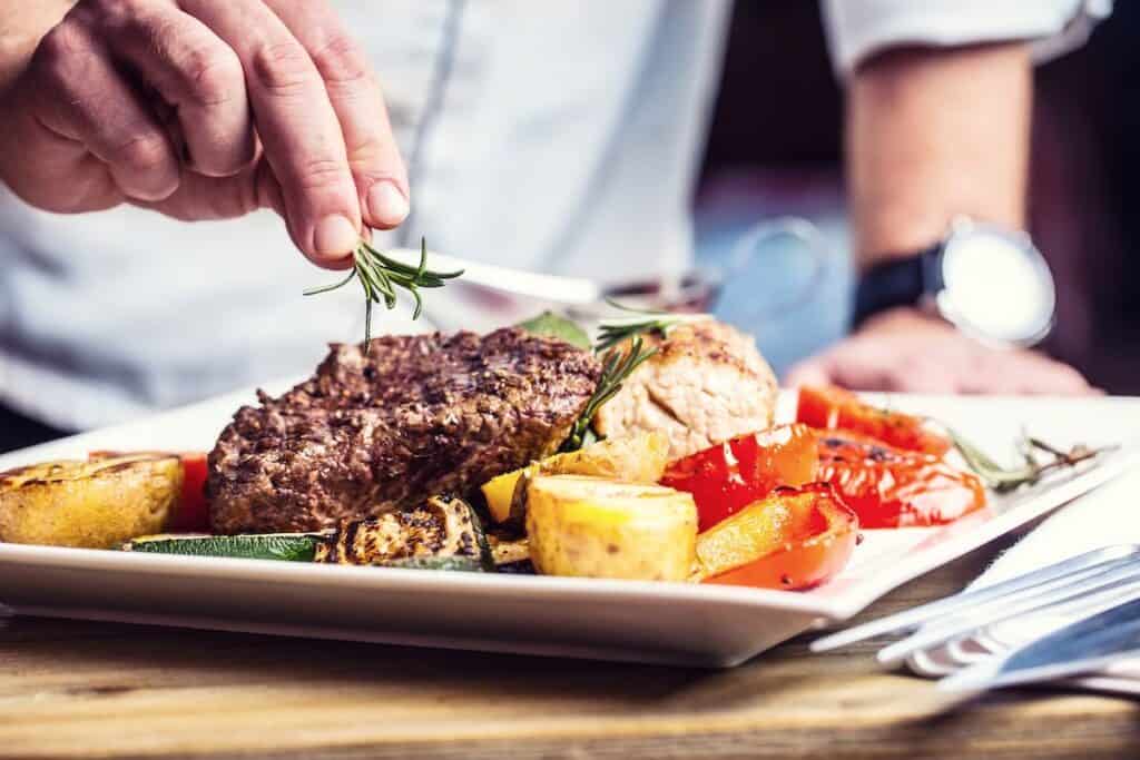 chef putting garnish on beef