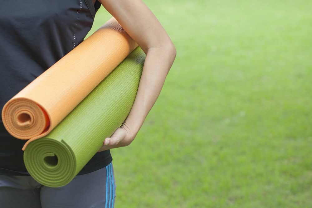 woman holding two yoga mats