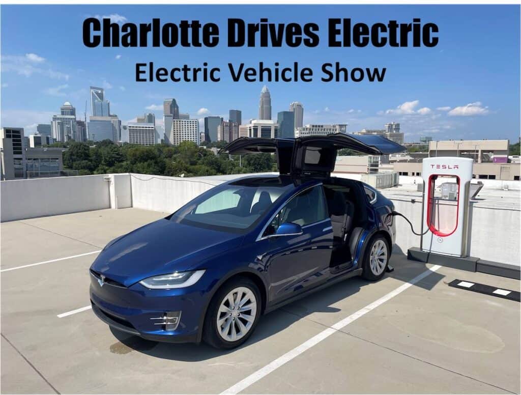Blue electric car being charged on the top of a parking deck, with Charlotte skyline in background