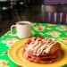 Pink pancakes on a yellow plate, with a cup of coffee