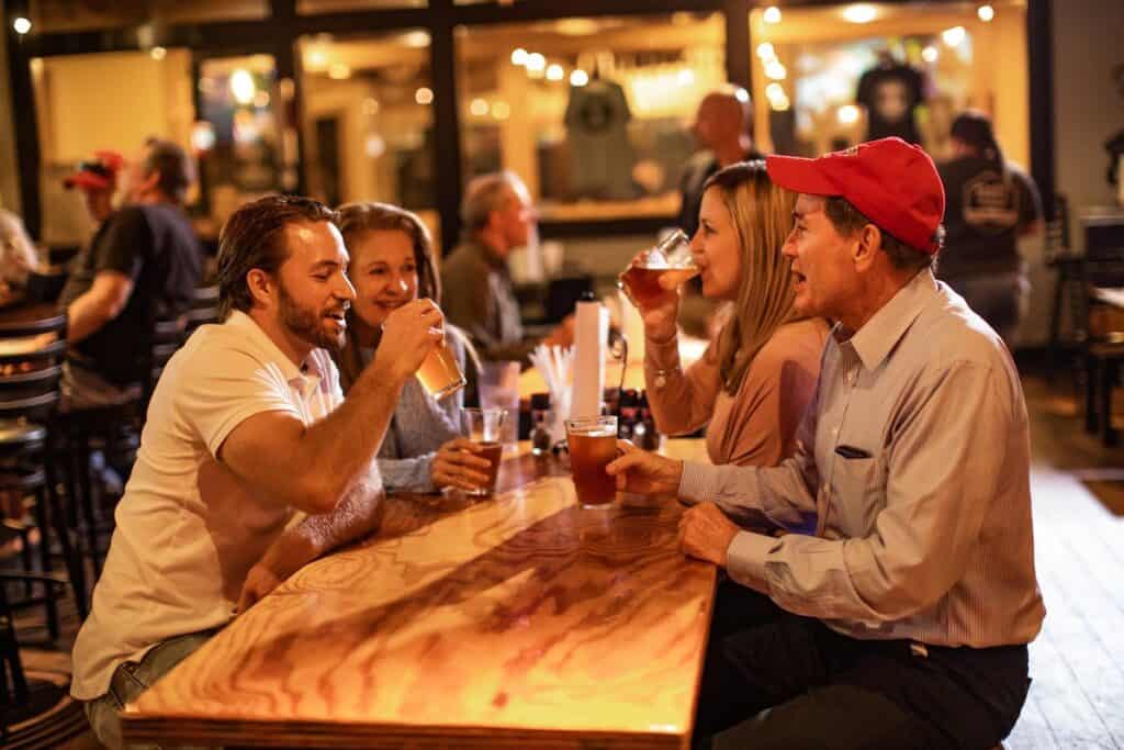 Four people enjoying beers at a wooden table