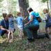 children and adults looking at the bark of a tree