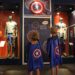 boys in capes pointing to shield at Marvel exhibit