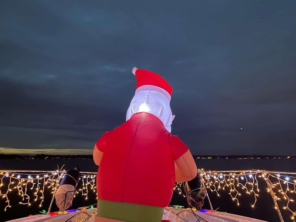 Santa inflatable on lighted boat on lake