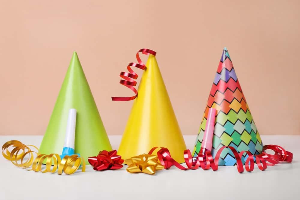 Colorful party hats, streamers and blowers on white table.