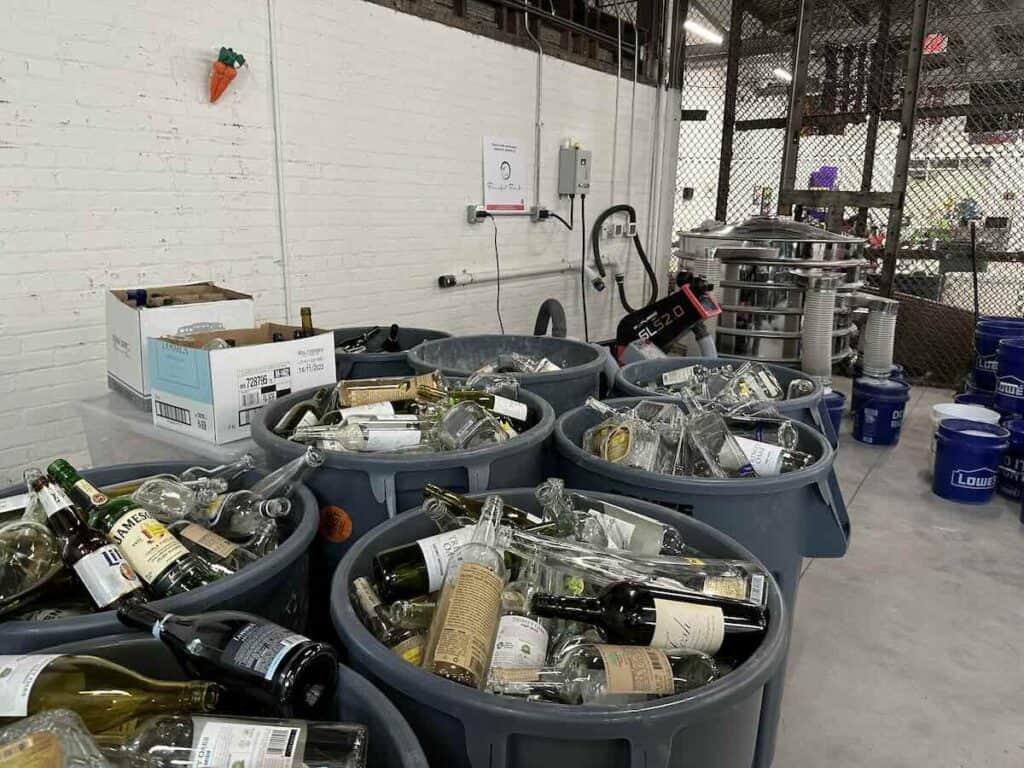 Bins of liquor bottles, with glass processing machines in the background