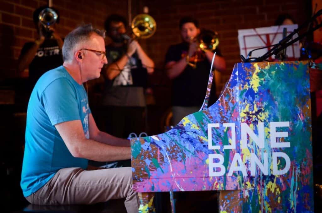 Musician playing piano painted in many colors.