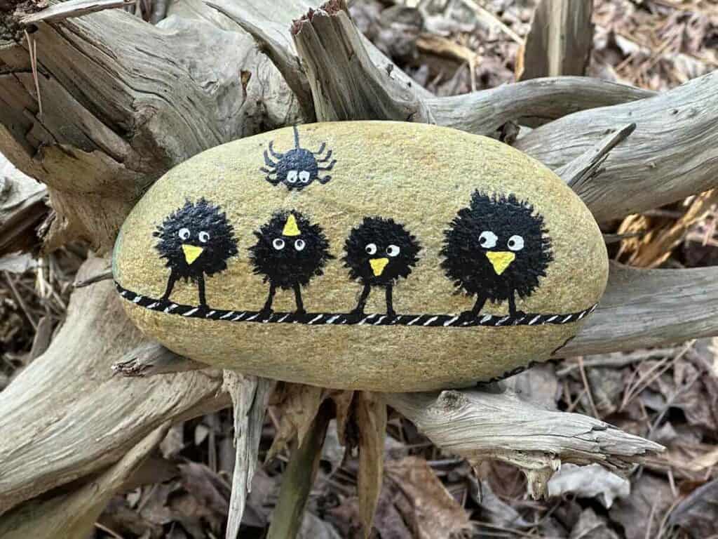 Rock with whimsical painting of birds and a spider