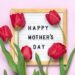 Felt board with text Happy Mother's day, red tulips bouquet on pink backround greeting holiday card Flat lay Top view.
