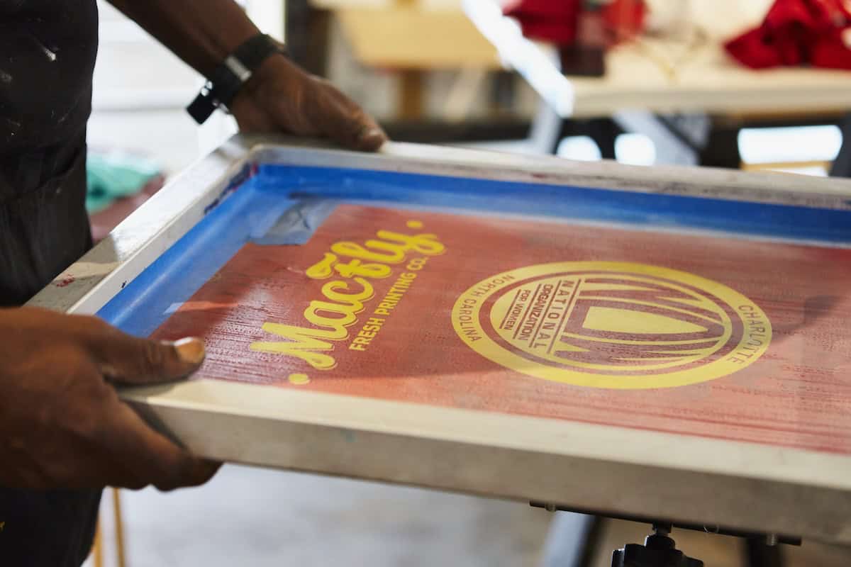 man holding wooden tray labeled as MacFly Fresh Printing Co.