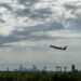 Plane taking off against backdrop of the Charlotte skyline, from the vantage point of CLT Airport Overlook