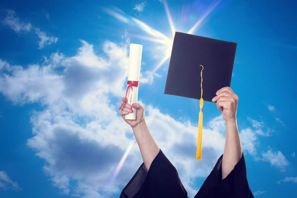 graduation cap and diploma in air