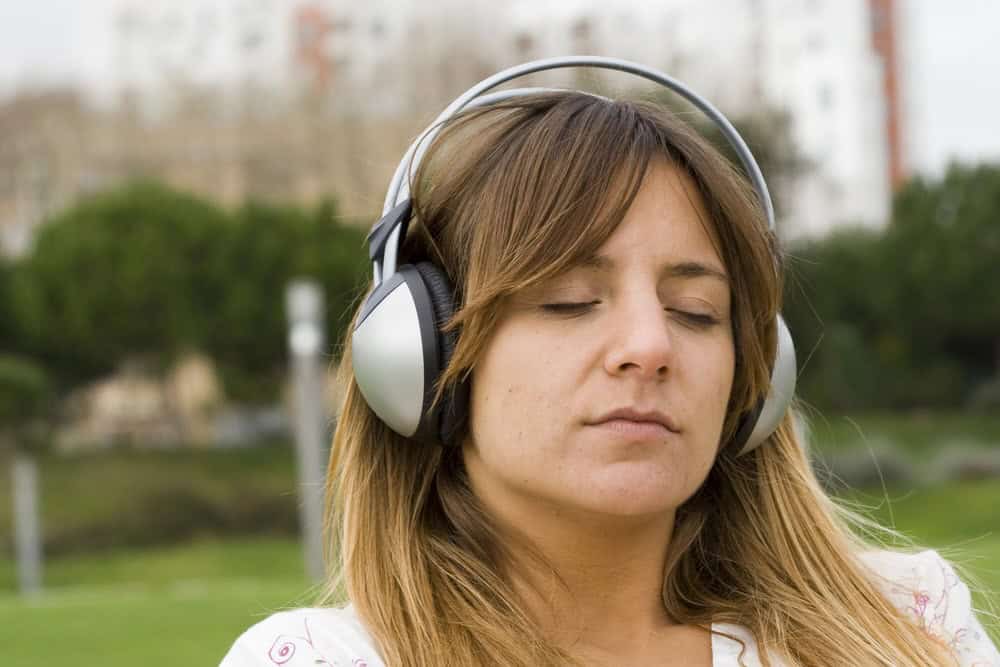 woman relaxing and listening music in a park