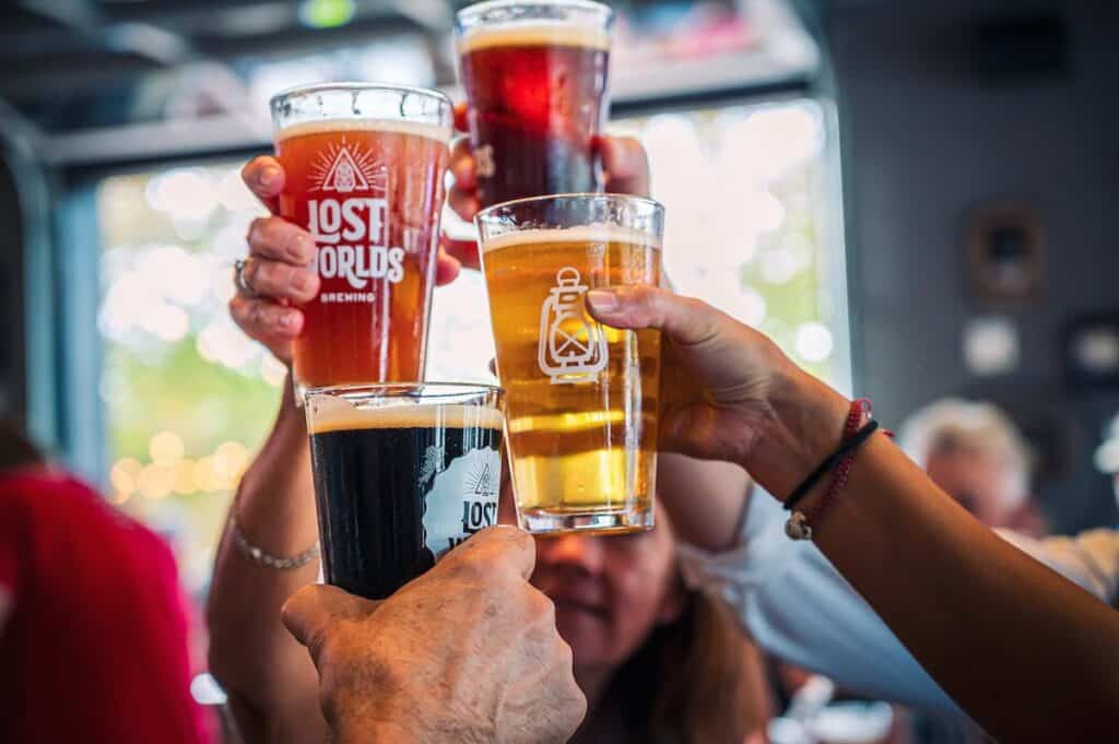 hands holding four beer glasses