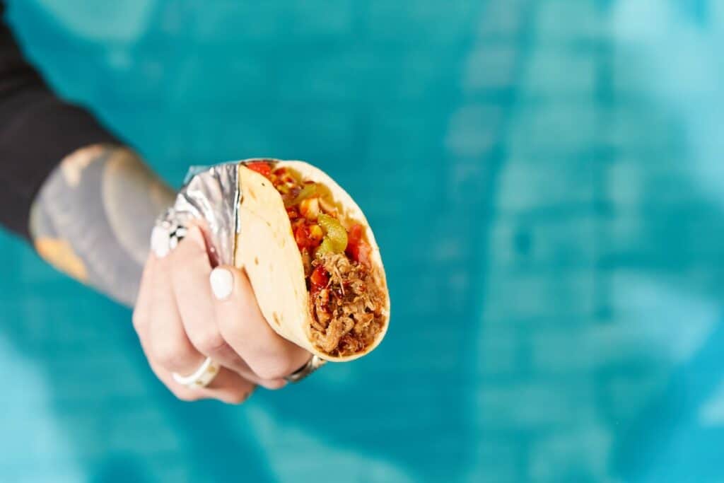 hand holding taco, with blue background