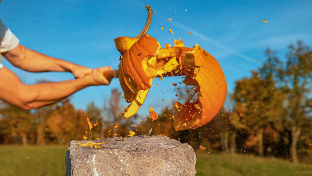man smashing pumpkin with axe