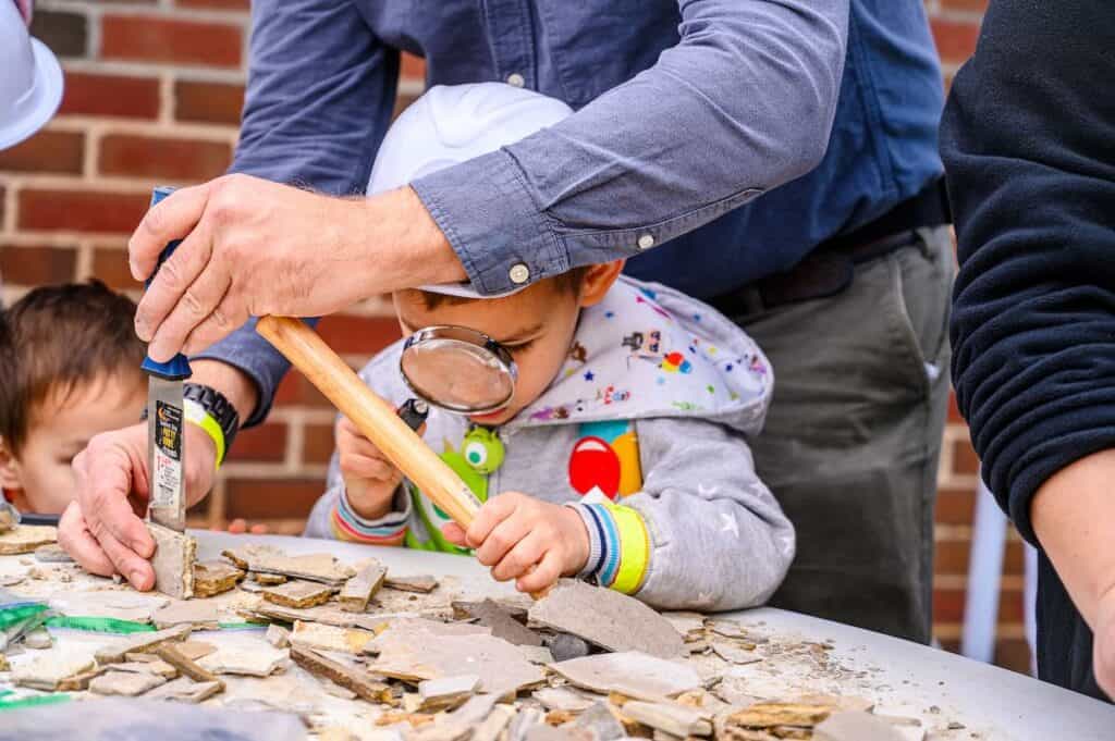 child looking at fossils through magnifying glass