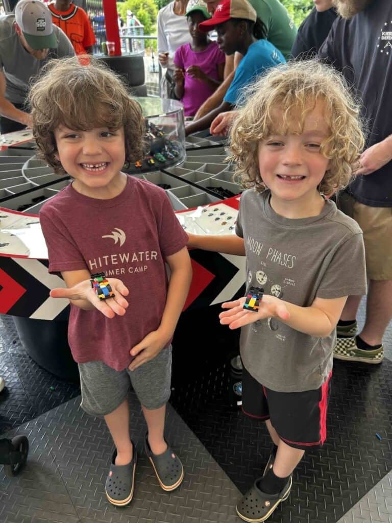 Two boys holding the Lego cars that they built