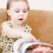 toddler sitting on couch reading book
