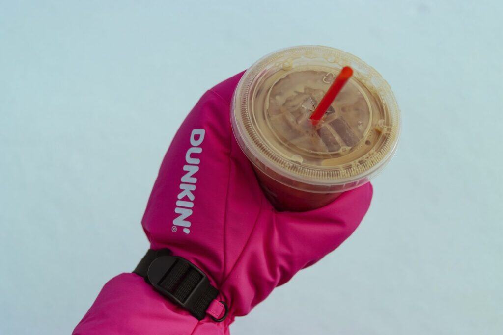 Hand with red Dunkin' glove holding a coffee