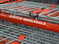 Close-up picture of shopping cart with red handle that says "Costco"