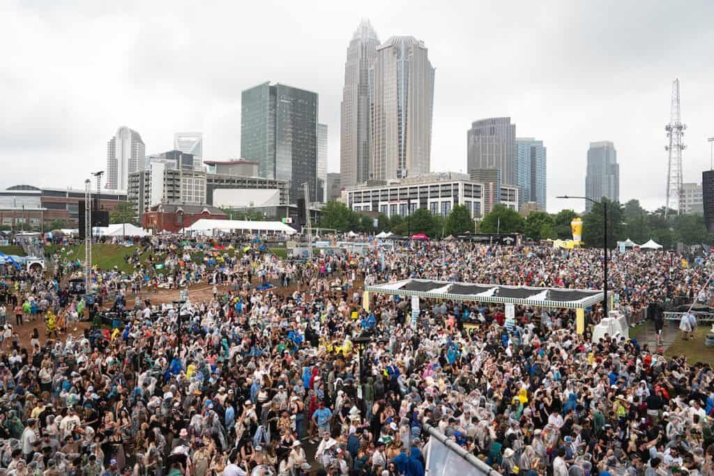 crowd in First Ward Park for music. Charlotte skyline in the background