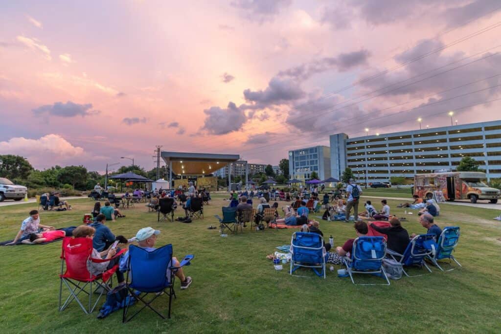people watching a concert in a park at sundown