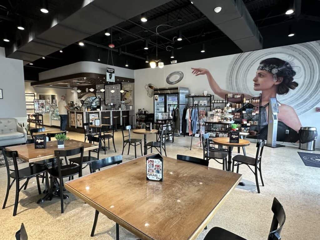 Interior of Percantile & Creamery, showing 20s-themed mural tables and chairs, merchandise and counter
