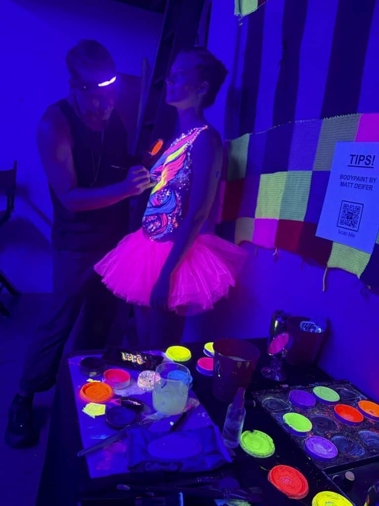 Artist painting woman under black light