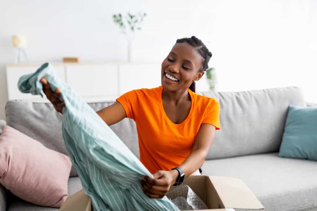 Woman smiling at shirt she's taking out of a box