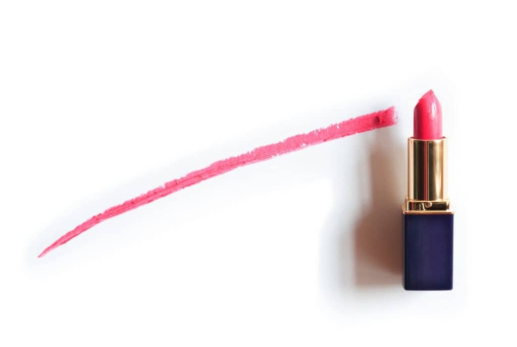 Red lipstick near painted line on white background