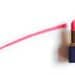 Red lipstick near painted line on white background