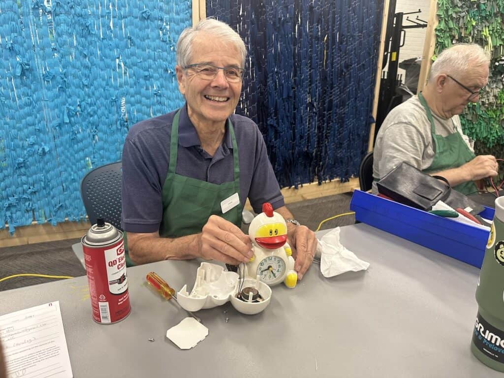 Man fixing duck or chicken alarm clock at Repair Cafe Charlotte
